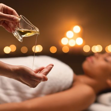 Therapist applying massage oil on hands before therapy